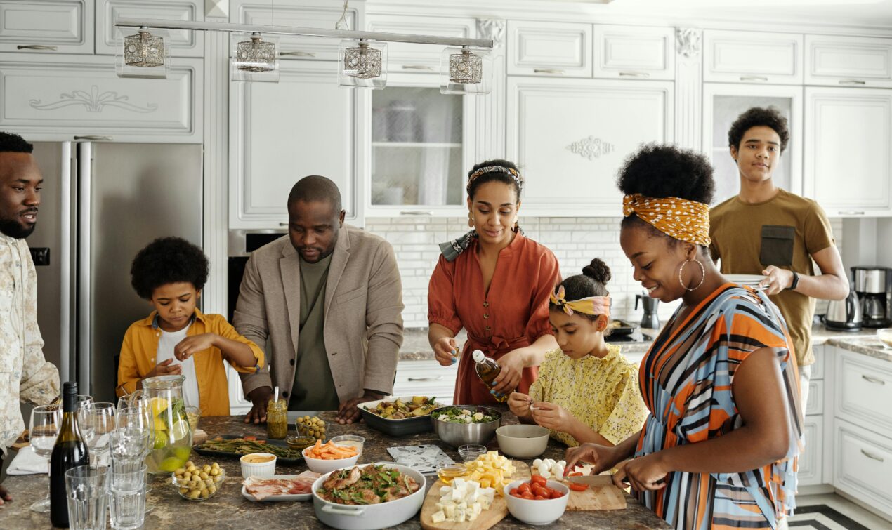 Mom making a meal surrounded by family and friends in the kitchen